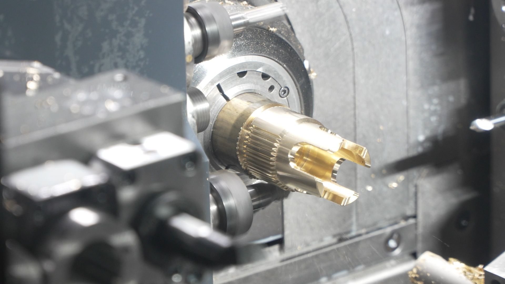 Close-up of a precision-machined metal part being cut inside a Tsugami Swiss-type lathe, showing the workpiece held in the spindle during machining.