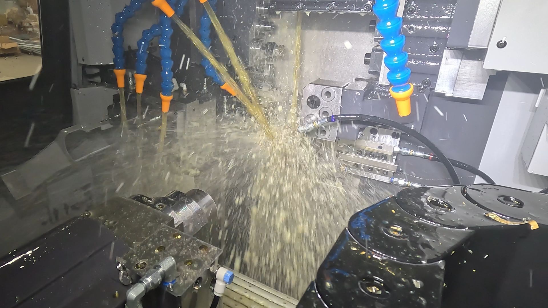 Interior view of a Tsugami Swiss-type lathe cutting a metal part with multiple high-pressure coolant lines spraying the machining area.